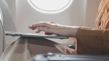 Traveling and technology. Flying at first class. Pretty young businees woman working on laptop computer while sitting in airplane. video