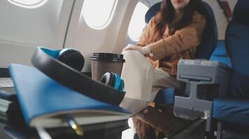 An Asian businesswoman in a semi-formal suit is using a tablet to read and analyze business data while traveling to a meeting in business class on a plane. video