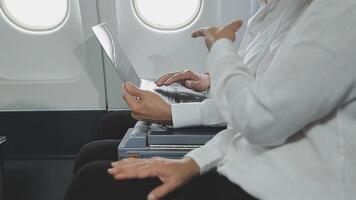 An Asian businesswoman in a semi-formal suit is using a tablet to read and analyze business data while traveling to a meeting in business class on a plane. video