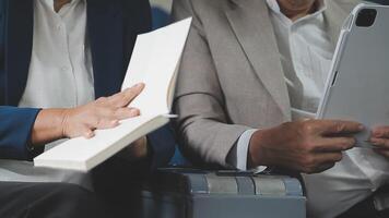 An Asian businesswoman in a semi-formal suit is using a tablet to read and analyze business data while traveling to a meeting in business class on a plane. video