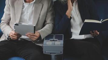 An Asian businesswoman in a semi-formal suit is using a tablet to read and analyze business data while traveling to a meeting in business class on a plane. video