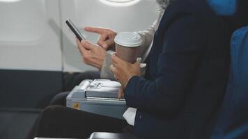 An Asian businesswoman in a semi-formal suit is using a tablet to read and analyze business data while traveling to a meeting in business class on a plane. video