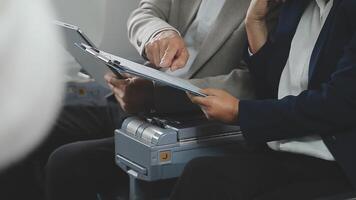 An Asian businesswoman in a semi-formal suit is using a tablet to read and analyze business data while traveling to a meeting in business class on a plane. video