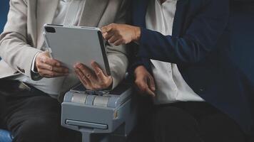 An Asian businesswoman in a semi-formal suit is using a tablet to read and analyze business data while traveling to a meeting in business class on a plane. video