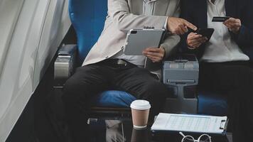An Asian businesswoman in a semi-formal suit is using a tablet to read and analyze business data while traveling to a meeting in business class on a plane. video
