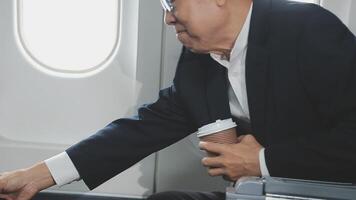 An Asian businesswoman in a semi-formal suit is using a tablet to read and analyze business data while traveling to a meeting in business class on a plane. video