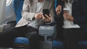 An Asian businesswoman in a semi-formal suit is using a tablet to read and analyze business data while traveling to a meeting in business class on a plane. video