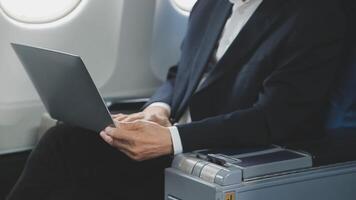 An Asian businesswoman in a semi-formal suit is using a tablet to read and analyze business data while traveling to a meeting in business class on a plane. video