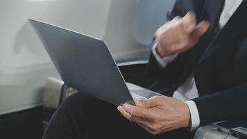 An Asian businesswoman in a semi-formal suit is using a tablet to read and analyze business data while traveling to a meeting in business class on a plane. video