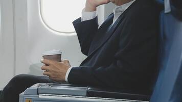 An Asian businesswoman in a semi-formal suit is using a tablet to read and analyze business data while traveling to a meeting in business class on a plane. video