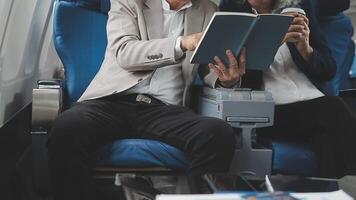 An Asian businesswoman in a semi-formal suit is using a tablet to read and analyze business data while traveling to a meeting in business class on a plane. video