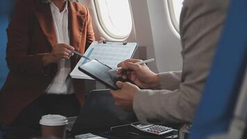 business people at meeting in private plane, asian businessman in suit discusses work with female colleague, manager shows graphs and reports to the boss, business partners fly in jet video