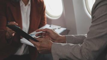 business people at meeting in private plane, asian businessman in suit discusses work with female colleague, manager shows graphs and reports to the boss, business partners fly in jet video