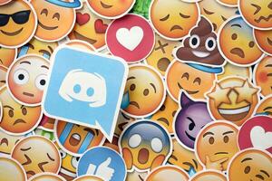 KYIV, UKRAINE - APRIL 20, 2024 Discord logo and large set of stickers with Emoji yellow faces. Emoji is a pictogram or smiley embedded in text and used in electronic messages photo