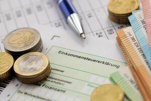 KYIV, UKRAINE - APRIL 20, 2024 Einkommensteuererklarung inscription from blank tax form and many euro banknotes on office table photo