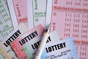 Lottery tickets of different colors and pen on blank bills with numbers for playing lottery photo