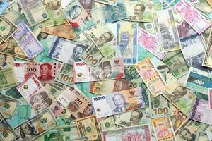 Many banknotes of different currency. Background of big amount of random money bills photo