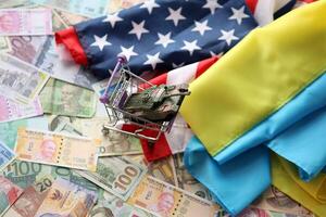 Toy tank on US flag and ukrainian flag on many banknotes of different currency photo