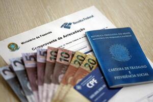 TERNOPIL, UKRAINE - JULY 7, 2023 Brazilian Work Permit document and Brazilian tax number card on table with tax form photo