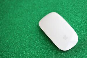 KYIV, UKRAINE - NOVEMBER 27, 2023 Apple Magic Mouse 3rd generation lies on sparkling glitter surface photo