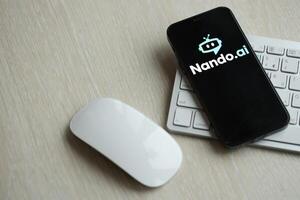 KYIV, UKRAINE - MARCH 17, 2024 NandoAI logo on iPhone display screen with apple keyboard and mouse on table photo