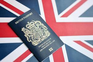 Blue British passport on national flag background close up photo