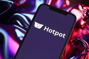 KYIV, UKRAINE - MARCH 17, 2024 Hotpot logo on iPhone display screen with background of artificial intelligence futuristic image photo