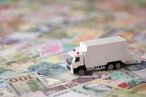 Delivery truck on many banknotes of different currency. Background of trucking or moving concept photo