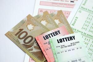 Lottery tickets lies with canadian dollars on gambling sheets with numbers for marking to play lottery photo