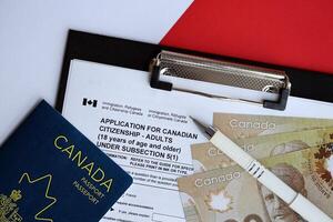 Application for Canadian citizenship for adults on table with pen, passport and dollar bills photo