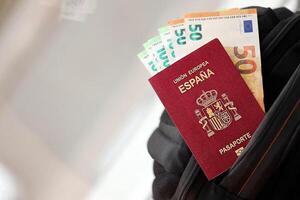 Red Spanish passport of European Union with money and airline tickets on touristic backpack photo