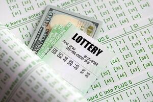 Green lottery tickets and US money bills on blank with numbers for playing lottery photo