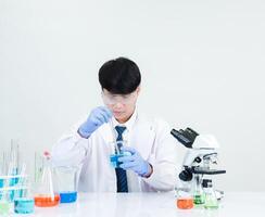 Portrait asian man student scientist Wearing a doctor gown in the lab looking hand at chemist. caused by mixing reagents in scientific research laboratories with test tubes and microscope on the table photo