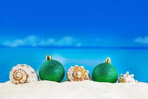 Shiny green balls with seashells on sand of beach. Christmas, New Year. Copy spaceShiny green balls with seashells on sand of beach. Christmas, New Year. Copy space photo