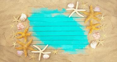 Blue boards on beach sand with starfish and shells with place for text. Banner. Vacation, travel concept. Copy space photo
