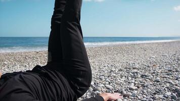 Boy Does Lower Abs With Legs Exercises On The Beach Near The Sea video