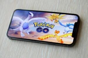 Pokemon GO mobile iOS game on iPhone 15 smartphone screen on wooden table during mobile gameplay photo