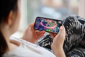 Honor of Kings mobile iOS game on iPhone 15 smartphone screen in female hands during mobile gameplay photo