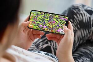 Clash of Clans mobile iOS game on iPhone 15 smartphone screen in female hands during mobile gameplay photo