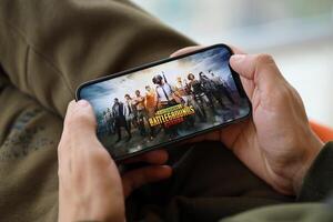 PUBG PlayerUnknowns Battlegrounds mobile iOS game on iPhone 15 smartphone screen in male hands during mobile gameplay photo