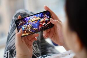Honor of Kings mobile iOS game on iPhone 15 smartphone screen in female hands during mobile gameplay photo