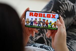 Roblox mobile iOS game on iPhone 15 smartphone screen in female hands during mobile gameplay photo