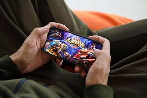 Honor of Kings mobile iOS game on iPhone 15 smartphone screen in male hands during mobile gameplay photo