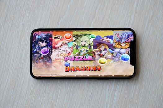 Puzzle and dragons mobile iOS game on iPhone 15 smartphone screen on wooden table during mobile gameplay photo