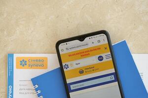 KYIV, UKRAINE - 4 MAY, 2023 Synevo medical analysis results and smartphone with synevo official website on screen photo