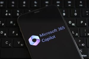 KYIV, UKRAINE - MARCH 17, 2024 Microsoft Copilot logo on iPhone display screen and MacBook keyboard photo