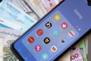 KYIV, UKRAINE - FEBRUARY 28, 2024 Dating apps icons on smartphone display and money bills photo