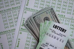 Green lottery tickets and US money bills on blank with numbers for playing lottery photo