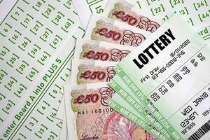 Green lottery tickets and Great Britain pounds money bills on blank with numbers for playing lottery photo