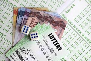 Green lottery tickets and brazilian reals money bills on blank with numbers for playing lottery photo